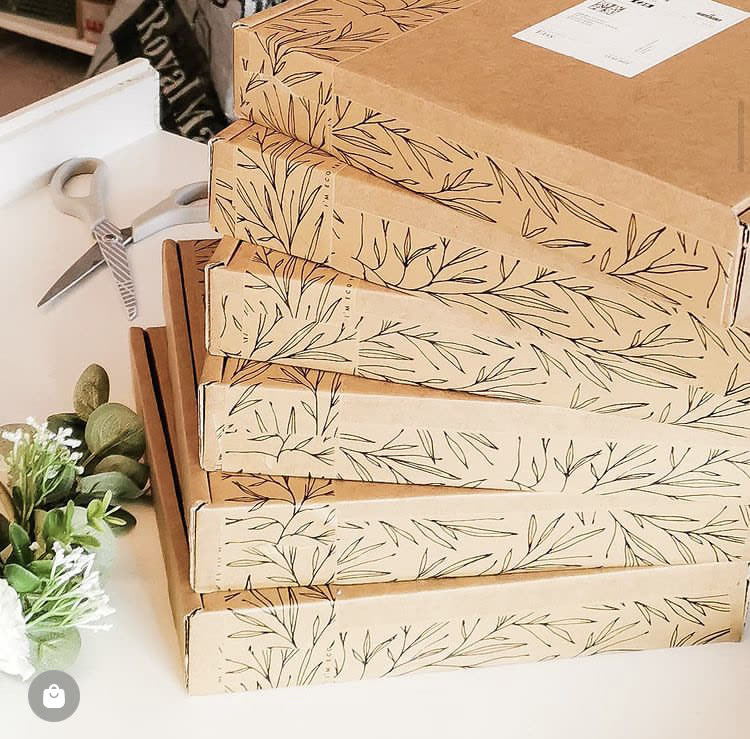 Stack of mailer boxes sealed with custom printed leaf-pattern eco tape